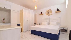 A bedroom with a bed, bedside tables, a dresser, and a hanging light fixture.