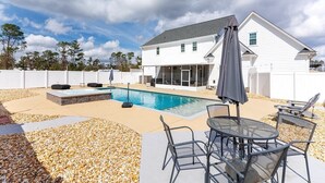 En bostadsfastighet med en swimmingpool, utemöbler och en täckt uteplats.