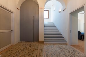 A hallway with a stone-patterned floor, a grey door, and a staircase with grey steps. - Tenuta Orsini 9+3, Emma Villas (Castiglione in Teverina)