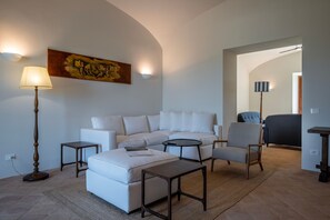 A living room with a sofa, armchairs, a coffee table, and a painting on the wall. - Tenuta Orsini 9+3, Emma Villas (Castiglione in Teverina)
