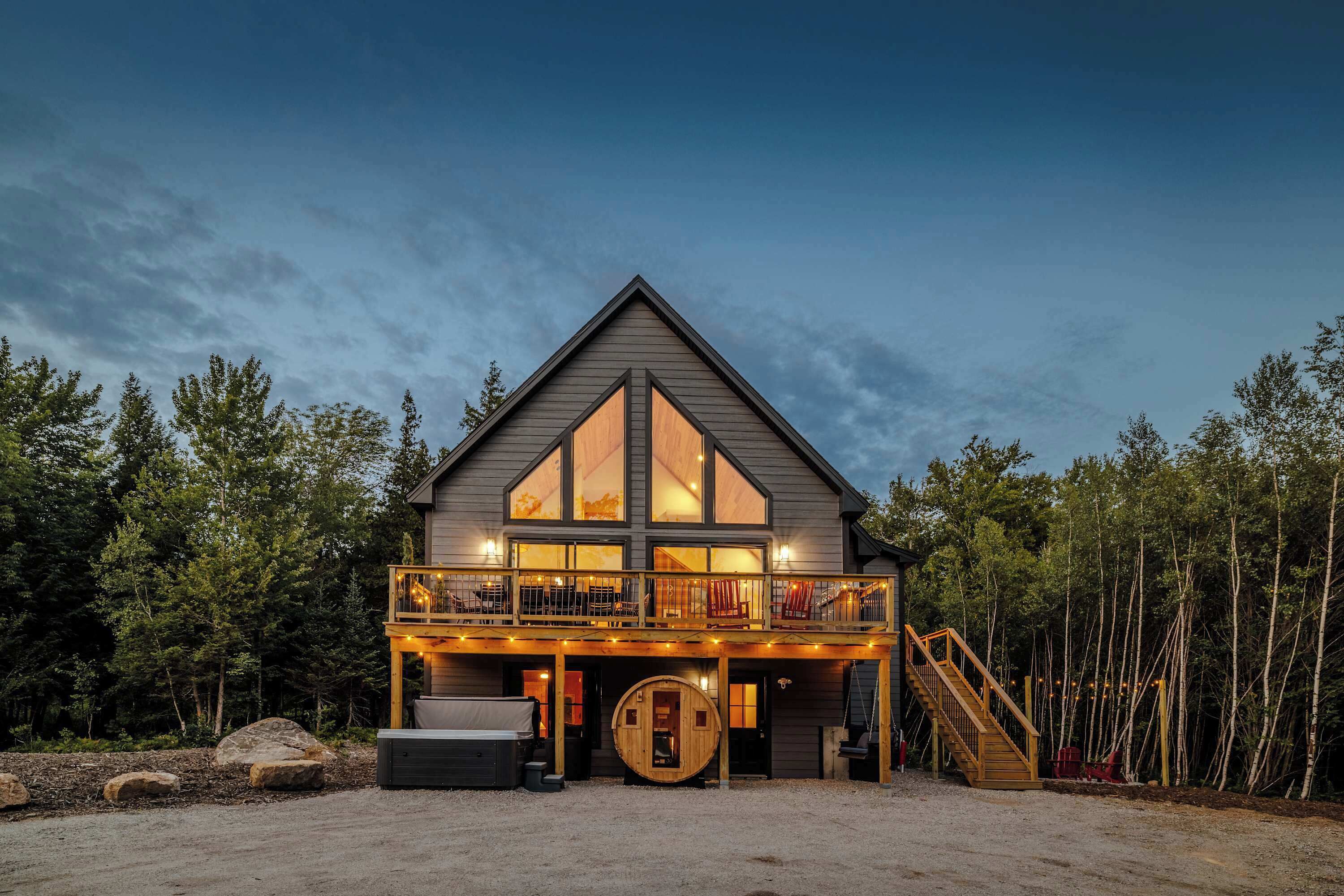 A two-story cabin with a balcony, a sauna, and a wooden deck.