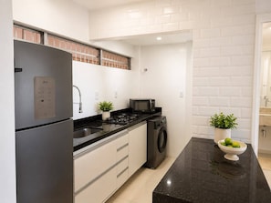 A modern kitchen with a stainless steel refrigerator, a microwave, a washing machine, and a sink. - Ocean View Ponta Verde (Maceió)