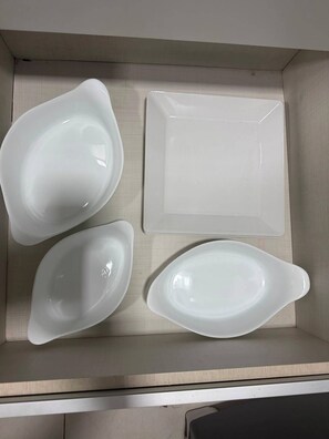 A storage box containing four white ceramic plates of different shapes. - Ocean View Ponta Verde (Maceió)