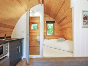 A compact, wooden cabin interior with a kitchenette, a single bed, and a small bathroom. - Ivy Tor (Tavistock)