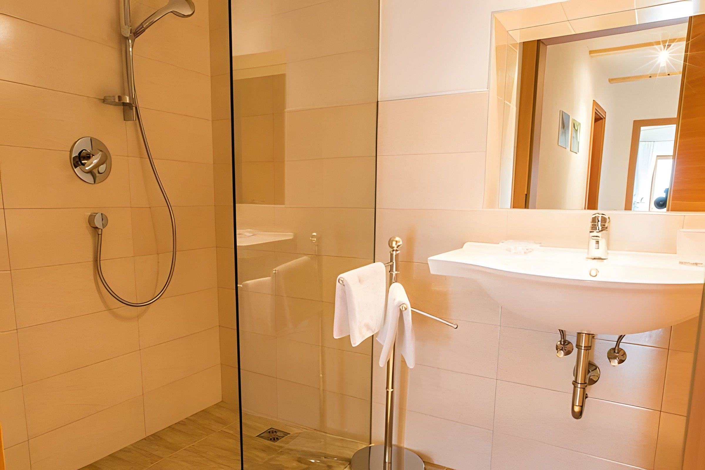 Une salle de bain moderne avec une douche à parois de verre, un lavabo blanc et un miroir au-dessus du lavabo.