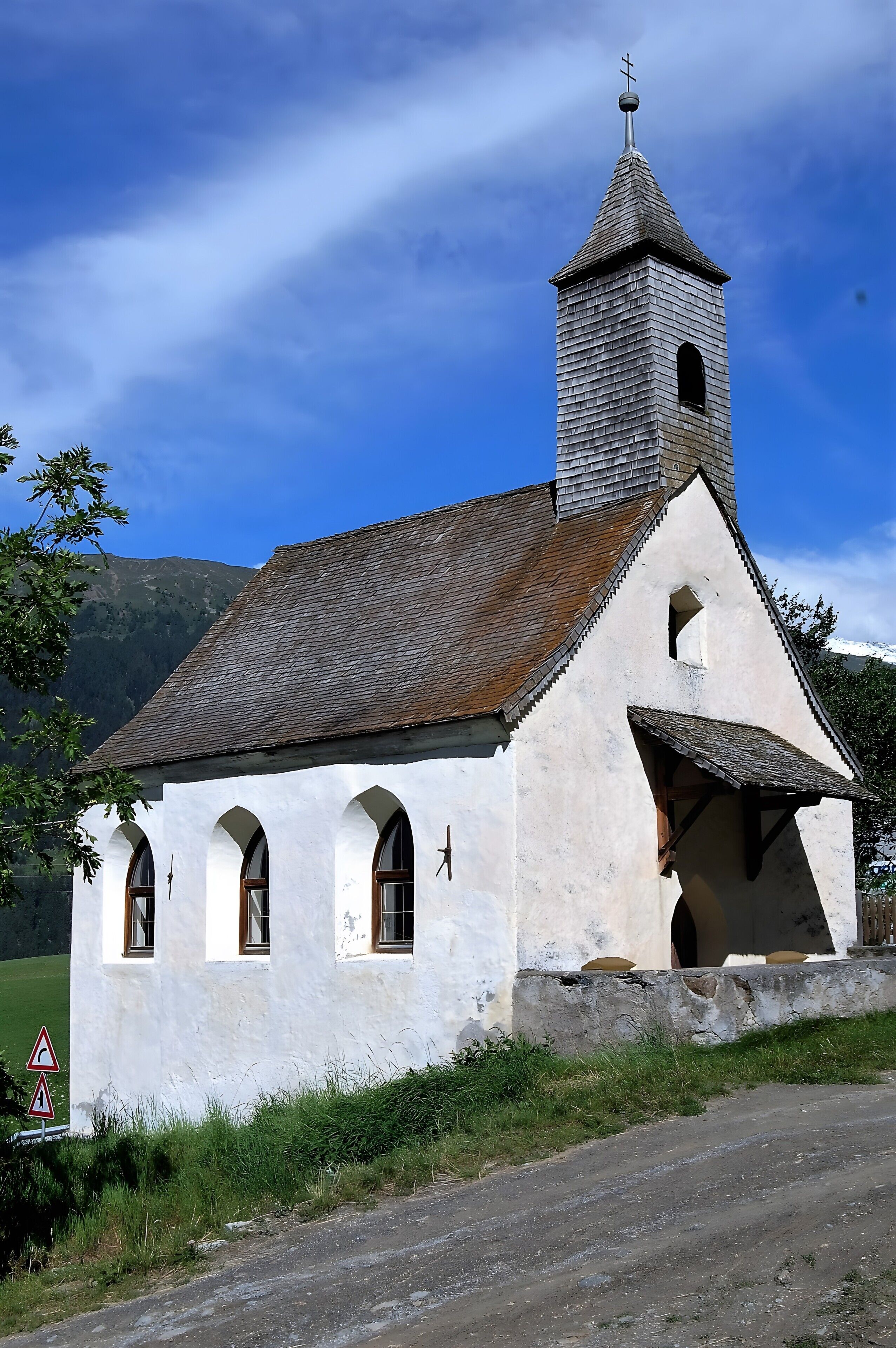 Una piccola chiesa bianca con un campanile e finestre ad arco.