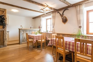 A rustic dining area with wooden tables and chairs, a wooden ceiling, and a mounted animal head on the wall. - Apartment Spitzige Lun (Ultimo)