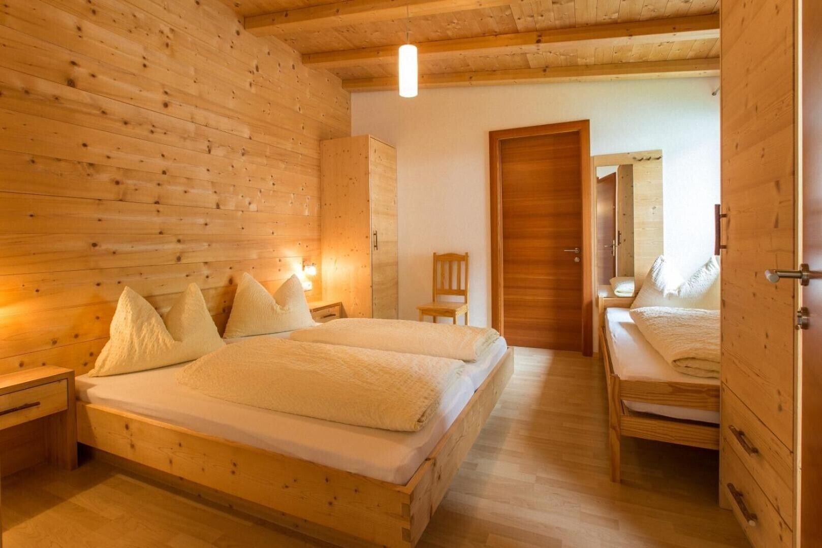 Una stanza in legno con un letto, una sedia e un armadio.