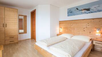 Een slaapkamer met een houten bed, een kledingkast, een spiegel en een wandlamp.