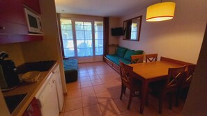 A compact kitchen with a dining area, a sofa, and a TV mounted on the wall. - House, near parking, heated pool, sleeps 4–5, ground floor, lake, nature, and fishing (Monflanquin)