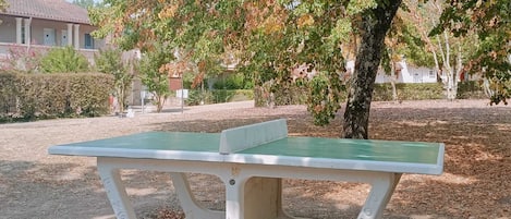 Un parc avec une table de pique-nique verte et un arbre.