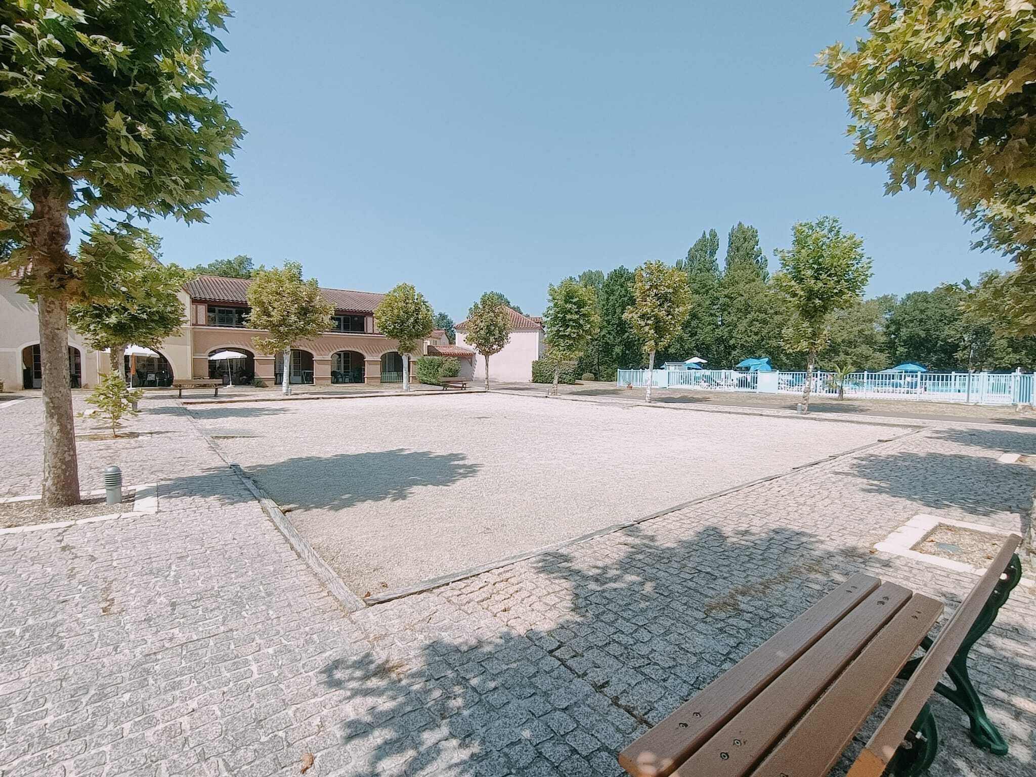 A courtyard with a paved area, a bench, and a building with arches.