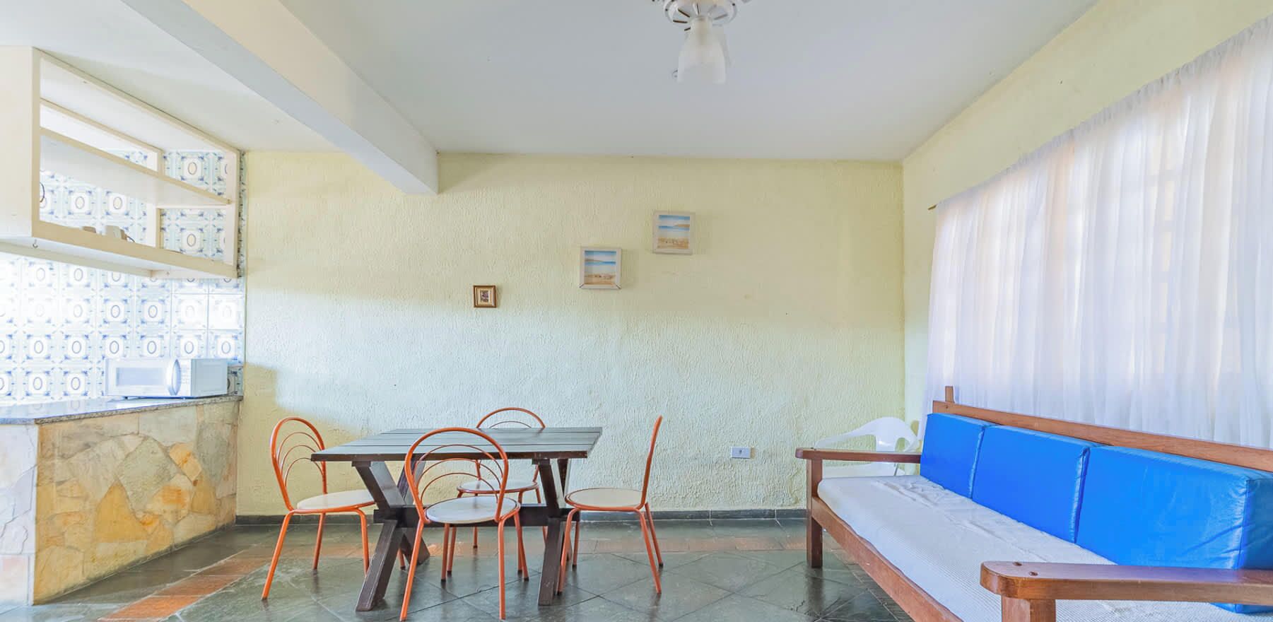 A room with a dining table, chairs, a sofa, a ceiling fan, and a tiled floor.