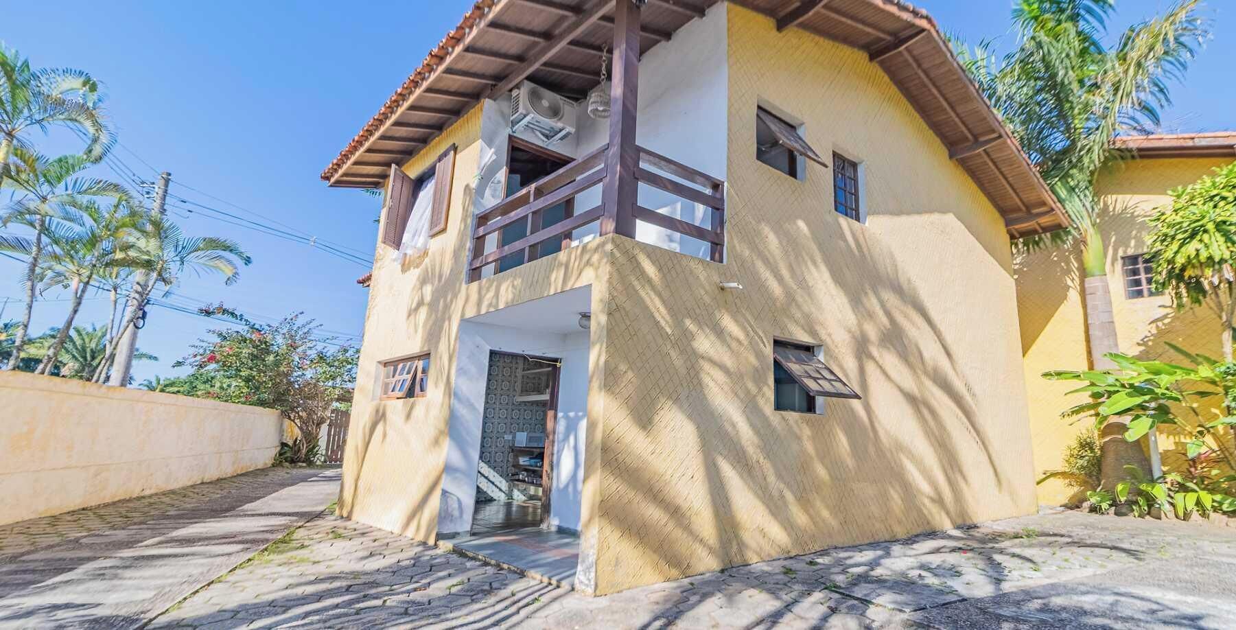 Un edificio de dos pisos con un balcón en el nivel superior, una entrada pequeña y un ventanal visible.