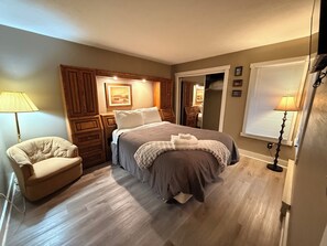 A bedroom with a bed, a chair, a nightstand, a lamp, and a window with blinds. - Poconos Ski-In Chalet on Telstar | Loft, Private Deck & Gas Grill (Lake Harmony)