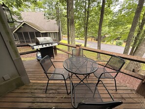 Eine Holzterrasse mit Grill, Sitzgelegenheiten im Freien und Blick auf eine Wohngegend.