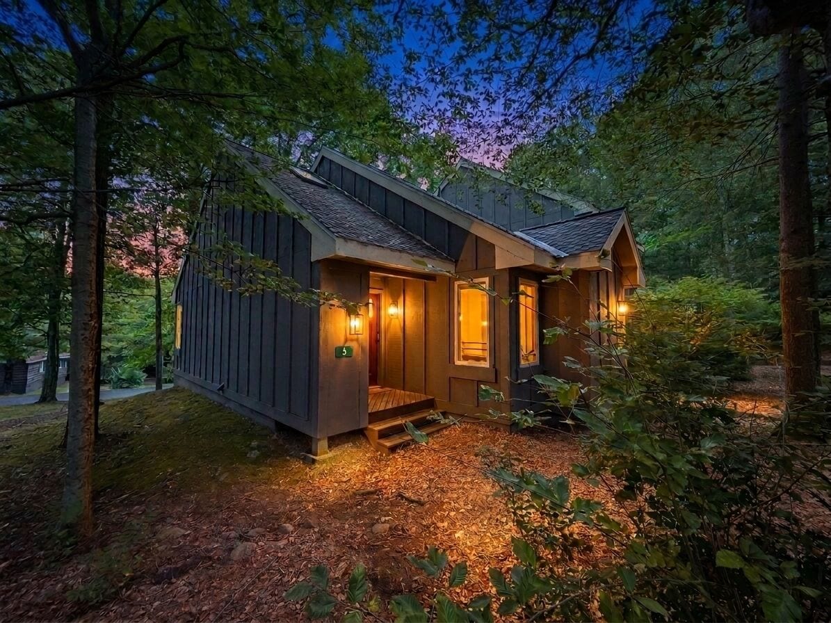 Een chalet met een veranda, een deur en een kleine trap die naar de ingang leidt.