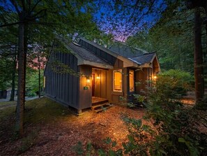 Eine Holzhütte mit Veranda, Tür und einer kleinen Treppe, die zum Eingang führt.