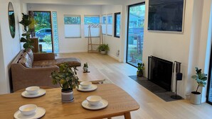 Uma sala de estar moderna com uma mesa de jantar, cadeiras, um sofá e uma lareira.