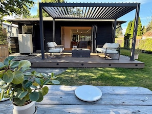 Eine überdachte Terrasse mit zwei Sofas, einem Couchtisch, einem Holzboden und einem Blumentopf.