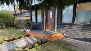 Uma casa moderna com um deck de madeira, porta da frente e um jardim bem cuidado.