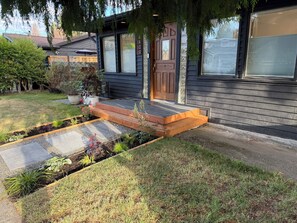 Ein modernes Haus mit Holzterrasse, Eingangstür und einem gepflegten Garten.