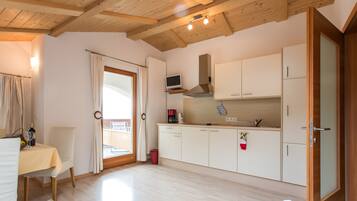 A compact kitchen with white cabinets, a built-in oven, and a window overlooking a balcony.