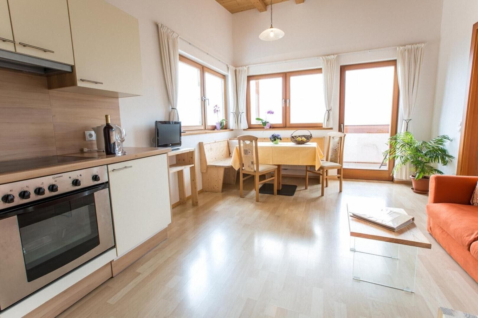 Moderni keittiö, jossa on liesi, pesuallas sekä ruokailutila tuoleineen ja pöytineen.