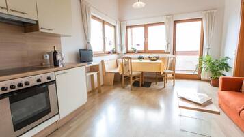 Moderni keittiö, jossa on liesi, pesuallas sekä ruokailutila tuoleineen ja pöytineen.