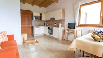 A modern kitchen with wooden cabinets, a microwave, a coffee maker, and a television.
