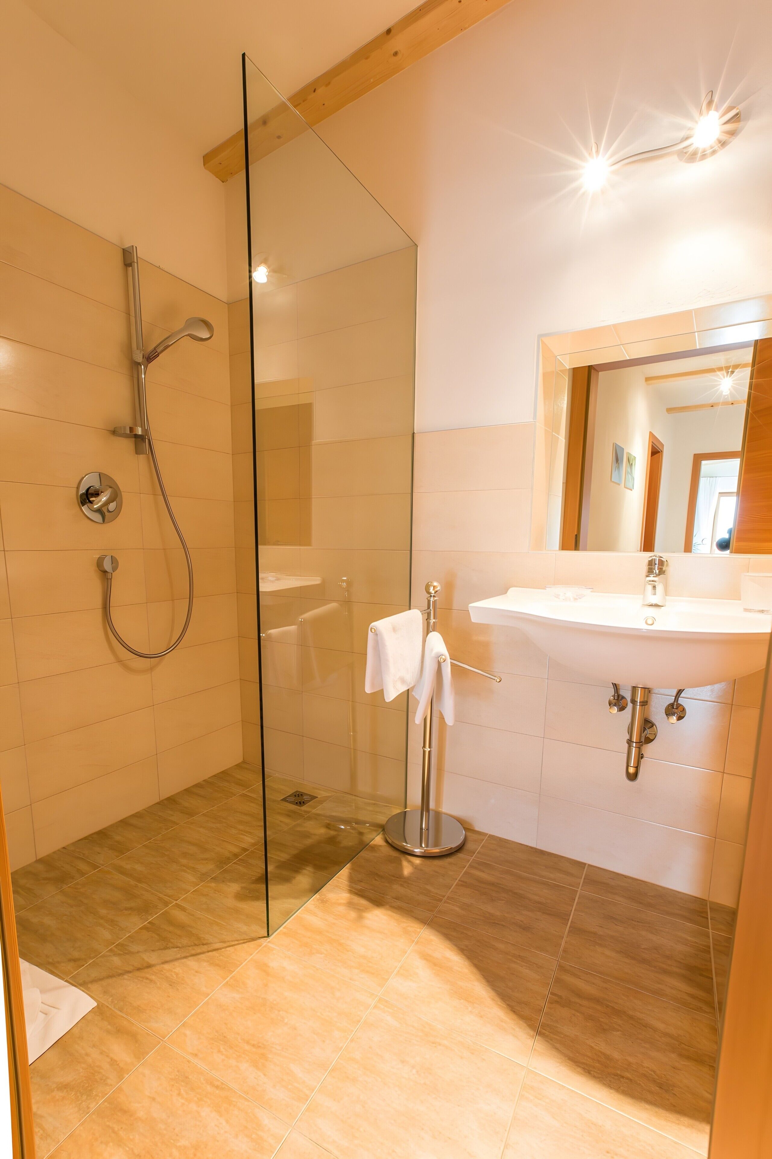 Une salle de bain moderne avec une douche à parois de verre, un lavabo avec un miroir et un porte-serviettes.