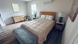 A bedroom with a large bed, bedside tables, a bench, a dresser, and a potted plant. - Ten Mile Tranquility! Our place is 1/2 mile from Marina with public boat dock. (Ten Mile)