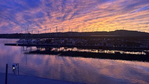 En lysthavn med fortøjede både, stille vand og en solnedgangshimmel.