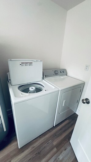 A compact laundry area with a front-loading washer and dryer, a small countertop, and a door. - Ten Mile Tranquility! Our place is 1/2 mile from Marina with public boat dock. (Ten Mile)