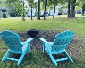 Two Adirondack chairs facing each other with a fire pit in between, set in a grassy yard with trees and houses in the background. - Ten Mile Tranquility! Our place is 1/2 mile from Marina with public boat dock. (Ten Mile)