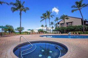A swimming pool with a tiled edge, surrounded by palm trees and lounge chairs, with a building in the background. - Kalama Terrace L203 South Kihei Retreat with Pool, Lanai, Ocean Nearby (Kihei)