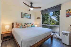 A bedroom with a bed, a ceiling fan, a window with a view, and a wall-mounted air conditioner. - Kalama Terrace L203 South Kihei Retreat with Pool, Lanai, Ocean Nearby (Kihei)