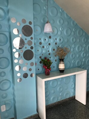 A reception area with a blue textured wall, a white console table, and a hanging light fixture. - 207 Apto 2 Qtos Lindo (Belém)