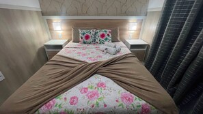 A neatly made bed with a floral duvet, two bedside tables with lamps, and a headboard with a crackled design. - 207 Apto 2 Qtos Lindo (Belém)