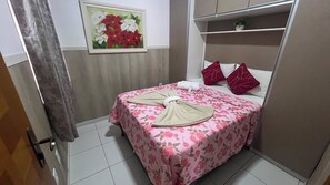 A hotel room with a bed, a painting, a shelf with a plant, and a door. - 207 Apto 2 Qtos Lindo (Belém)