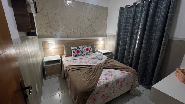 Ein Hotelzimmer mit einem Bett, Nachttischen, einem Spiegel und einem Badezimmer mit Vorhang.