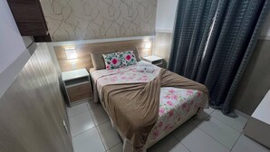 Ein Hotelzimmer mit Bett, Nachttischen, einer Kopfstütze, einer Wand mit Strukturmuster und einem Vorhang.