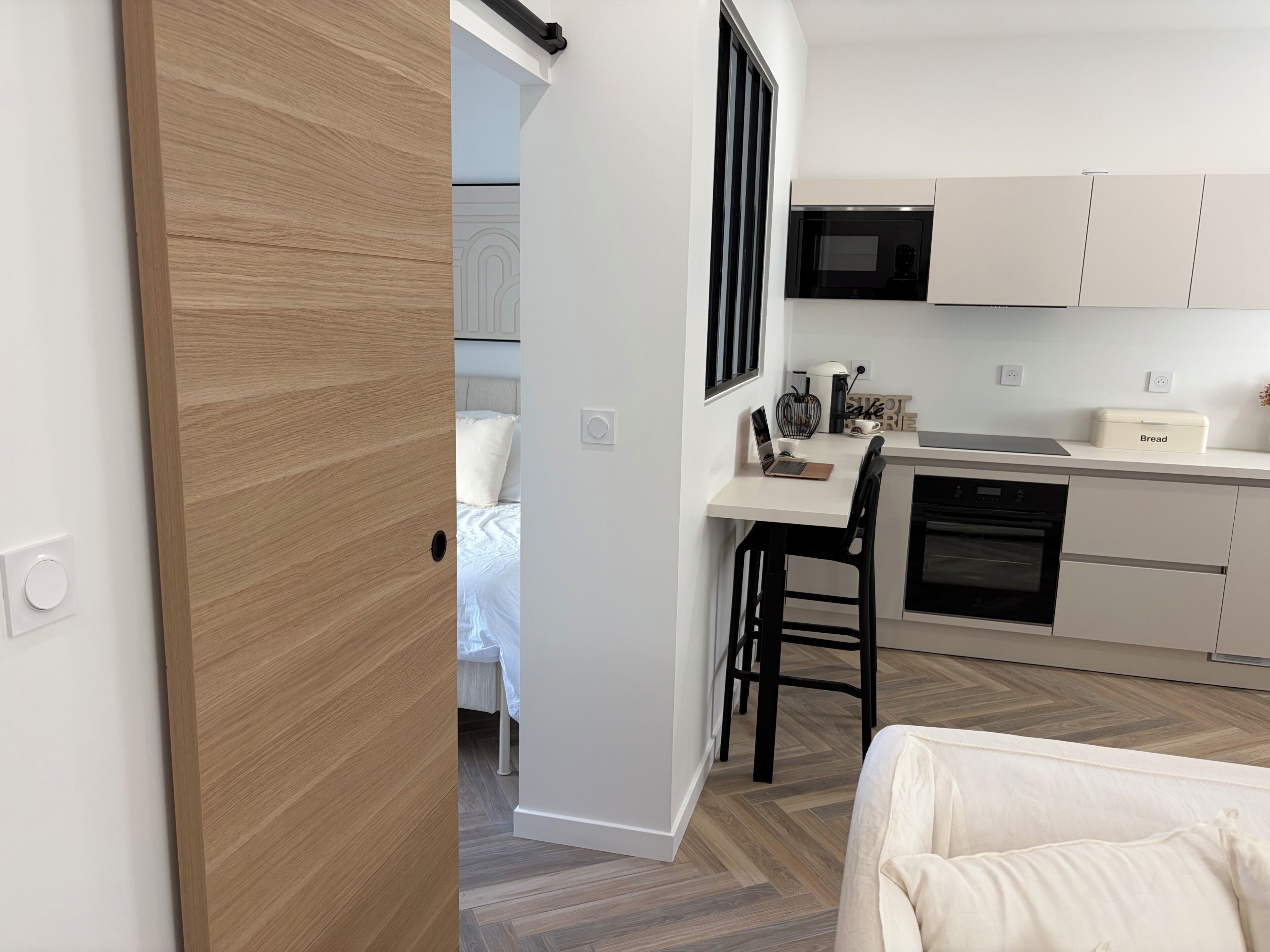 A modern kitchen with white cabinets, a microwave, and a coffee machine.