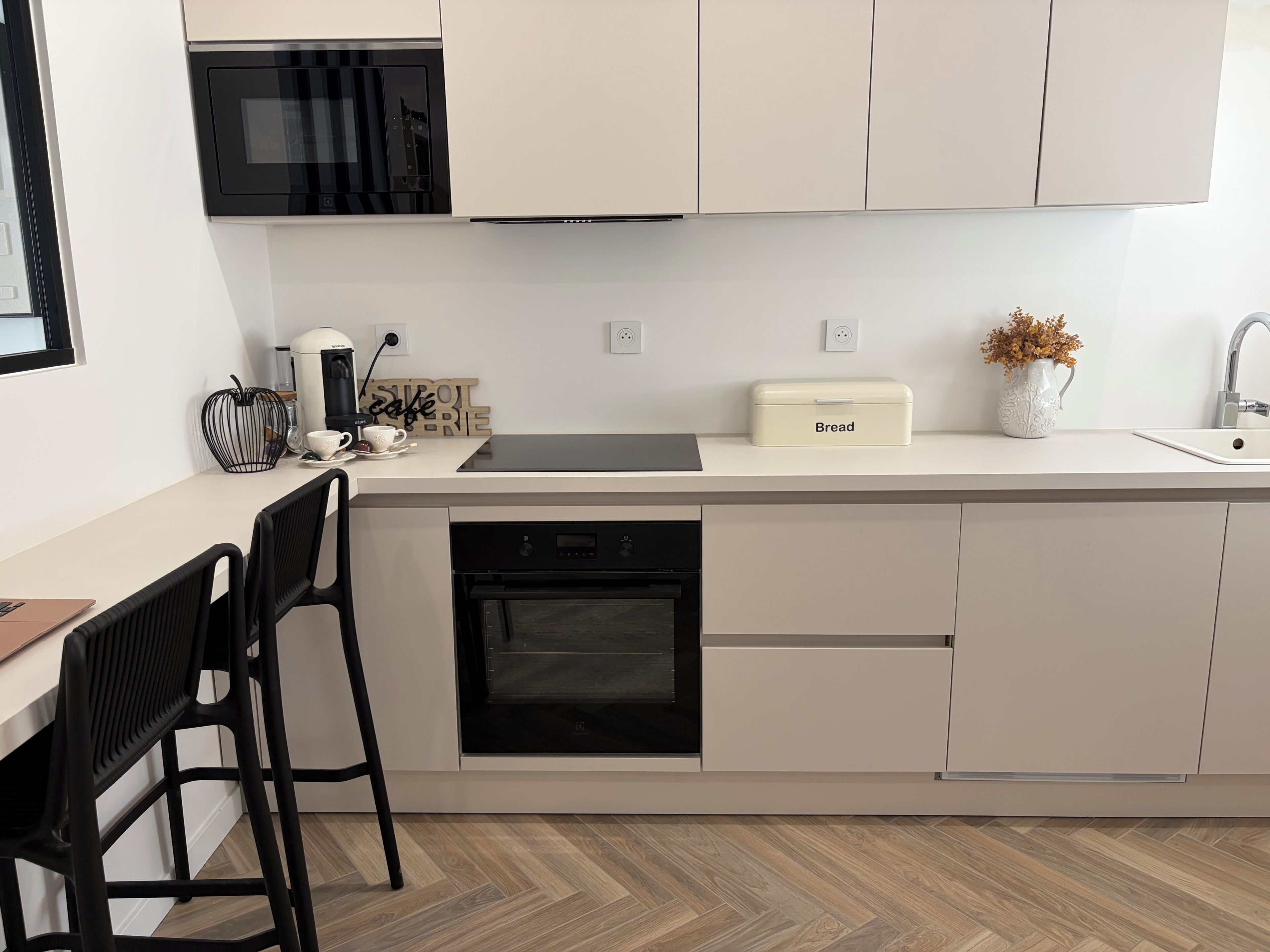 A modern kitchen with a microwave, oven, and a bread box on the counter.