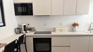 Una cocina moderna con microondas, horno y una panera sobre la encimera.