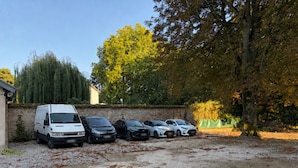 Un estacionamiento con una camioneta blanca y varios automóviles estacionados.