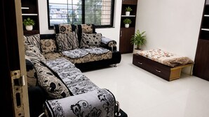 A modern living room with a sofa, a small bed, and built-in storage cabinets.