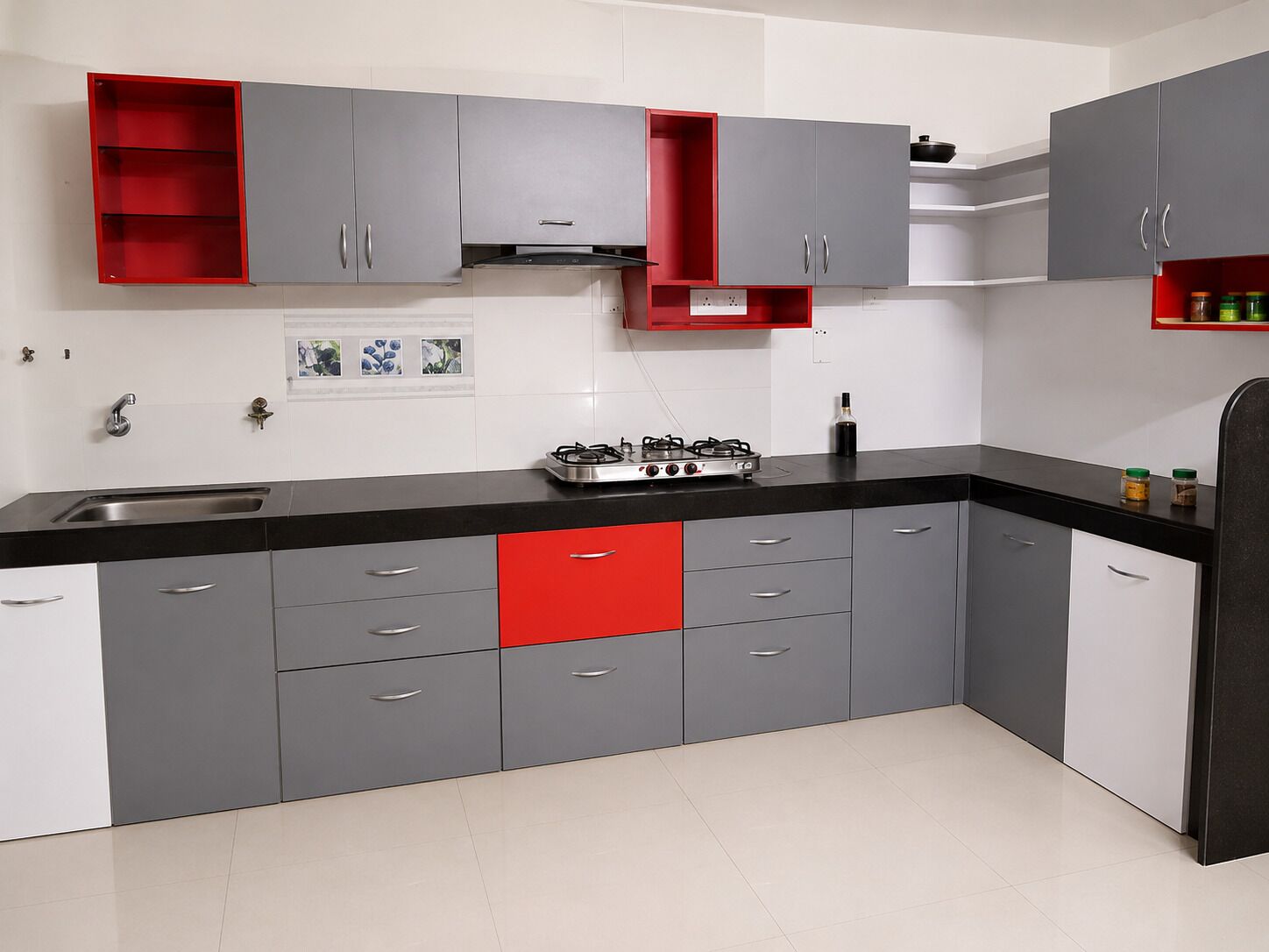 A kitchen with grey cabinets, a red lower drawer, a gas stove, and a black countertop.