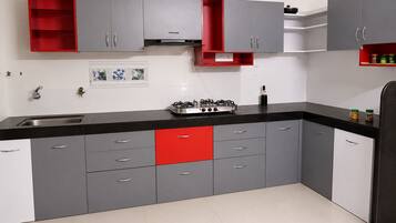 A kitchen with grey cabinets, a red lower drawer, a gas stove, and a black countertop.
