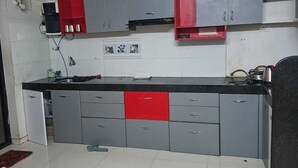 A kitchen with grey cabinets, a red countertop, and a ceiling fan.